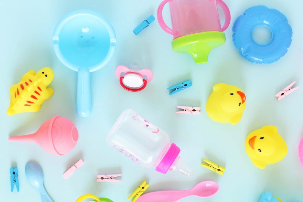 Bunch of baby items like a baby bottle, bath toys, and clips for an article about How To Get Free Baby Formula (11 Real Ways That Work)