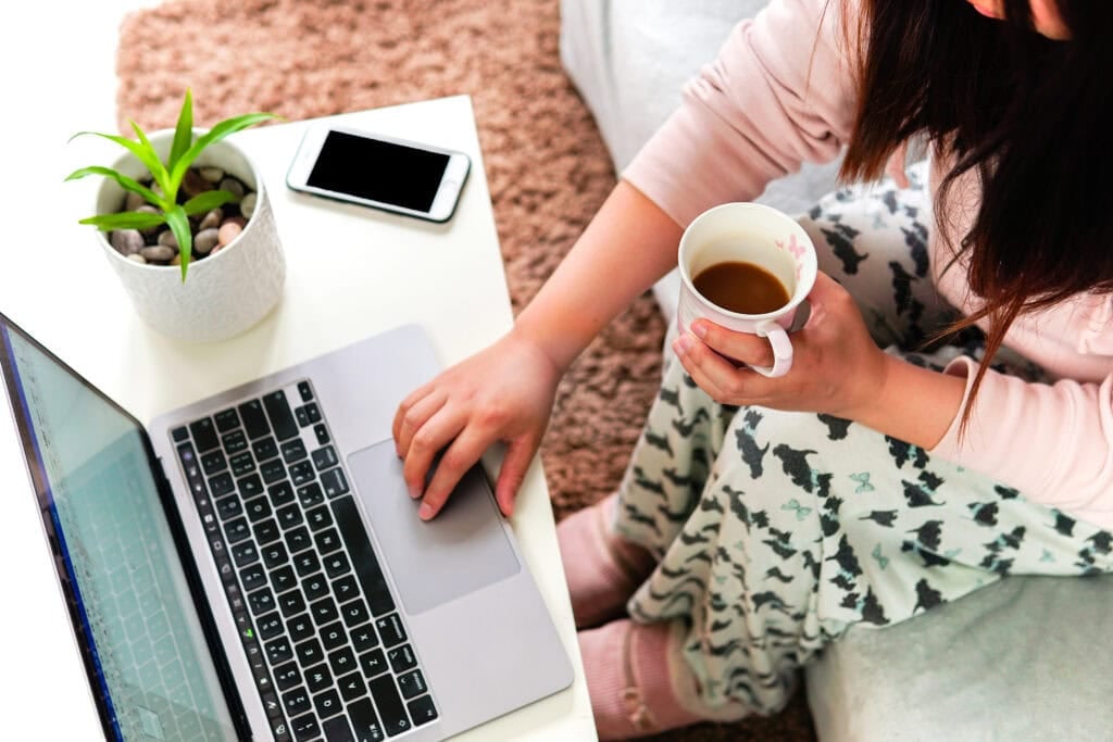 person working from home in pajamas with coffee in hand